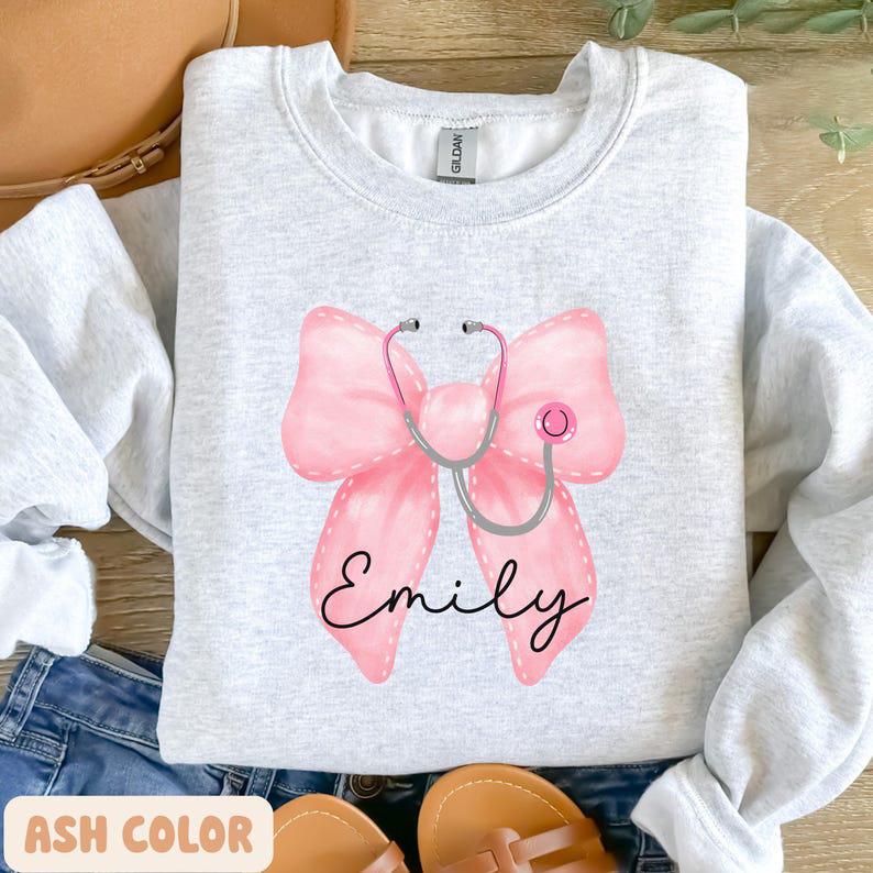 Custom Coquette Name Gift For Nurses, Healthcare Workers Sweatshirt, Pink Bow & Stethoscope Design, Nurse Bow Shirt, Christmas Nurse Gift, Unisex Shir